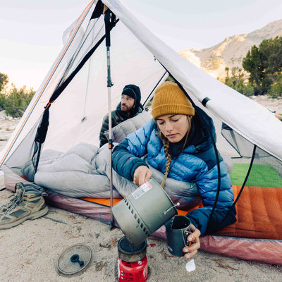 Two campers make tea while laying in the Hyperlite Mountain Gear Unbound 2P Tent
