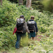 Hikers wearing the Hyperlite Mountain Gear Unbound 40 Pack hike through the ferns and shrubs